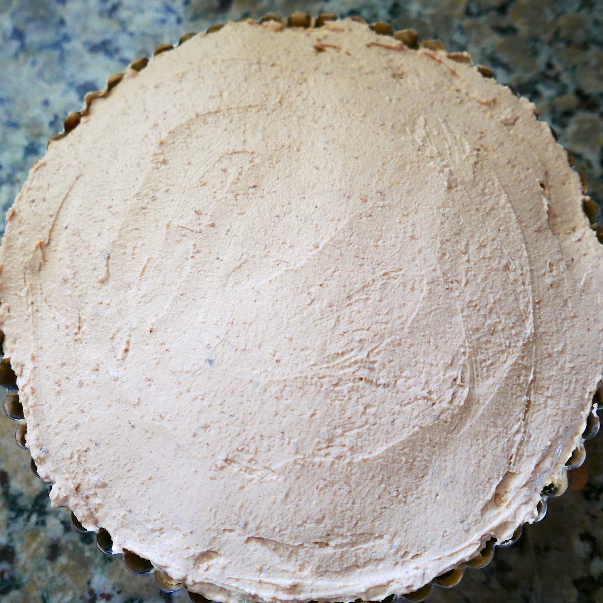 Peanut butter filling spread in tart pan.