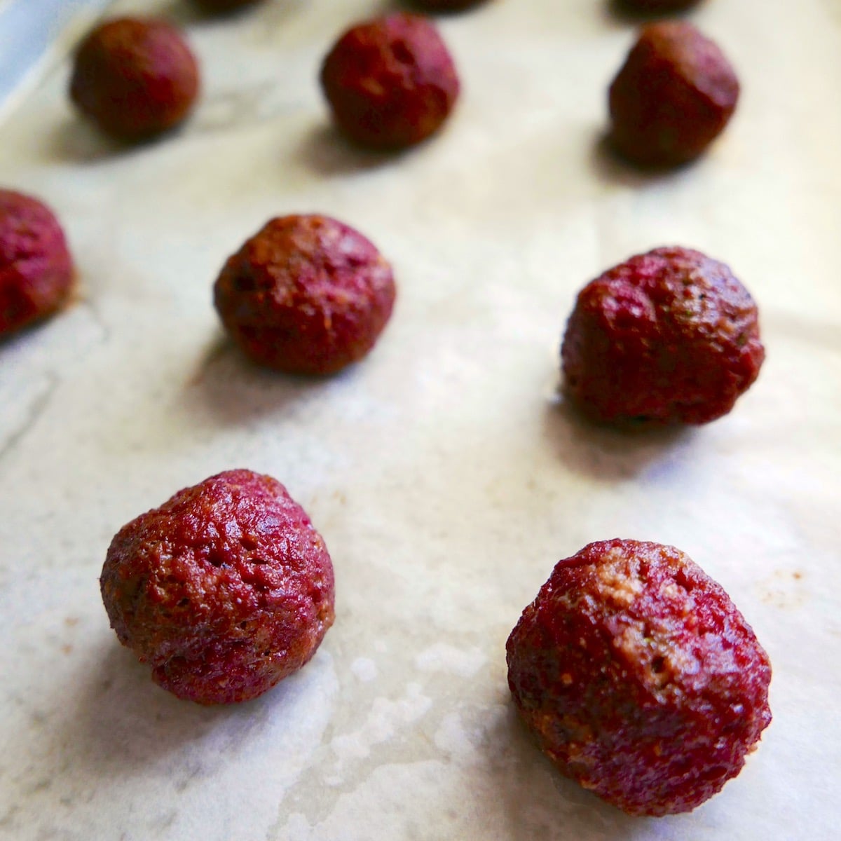 Baked meatballs on a baking sheet.
