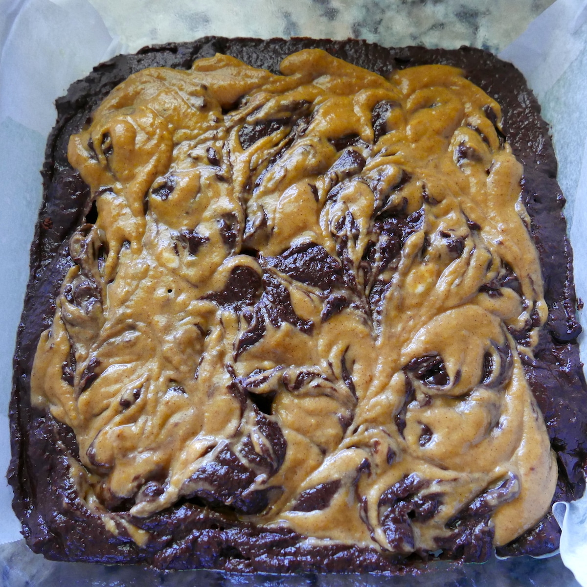 Brownie batter with pumpkin spice swirl in a baking dish.