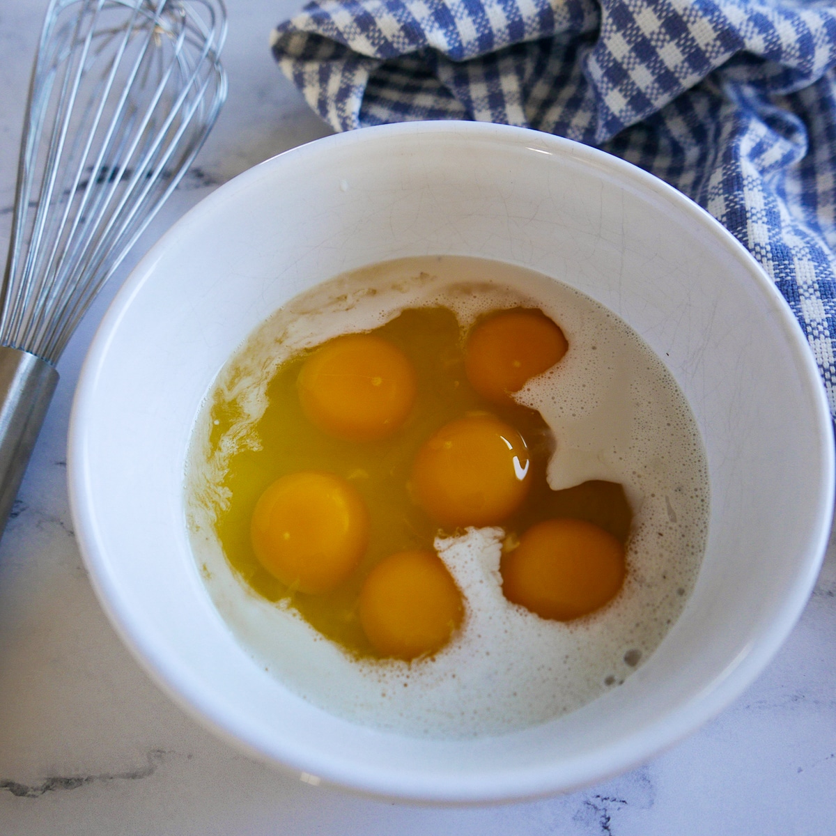 eggs-being-whisked.jpg Eggs, cream, salt, and pepper being whisked in a small white bowl.