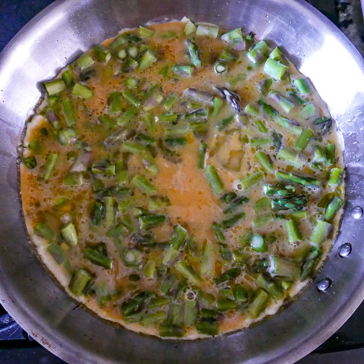 eggs cooking in pan with asparagus