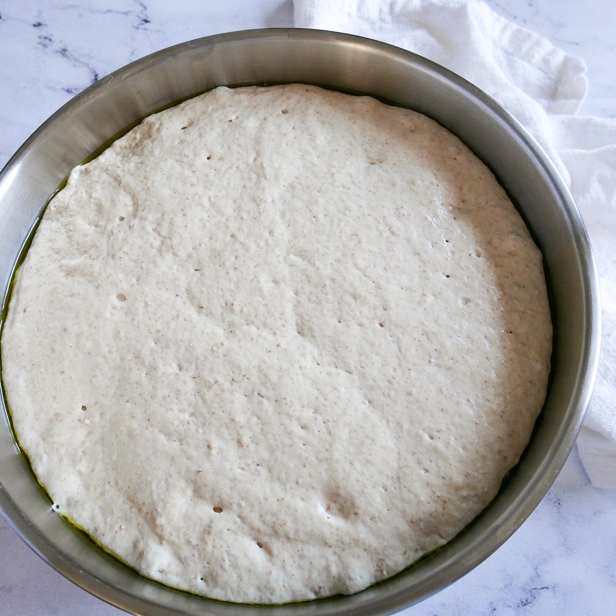 Focaccia dough in a mixing bowl after doubling in volume.
