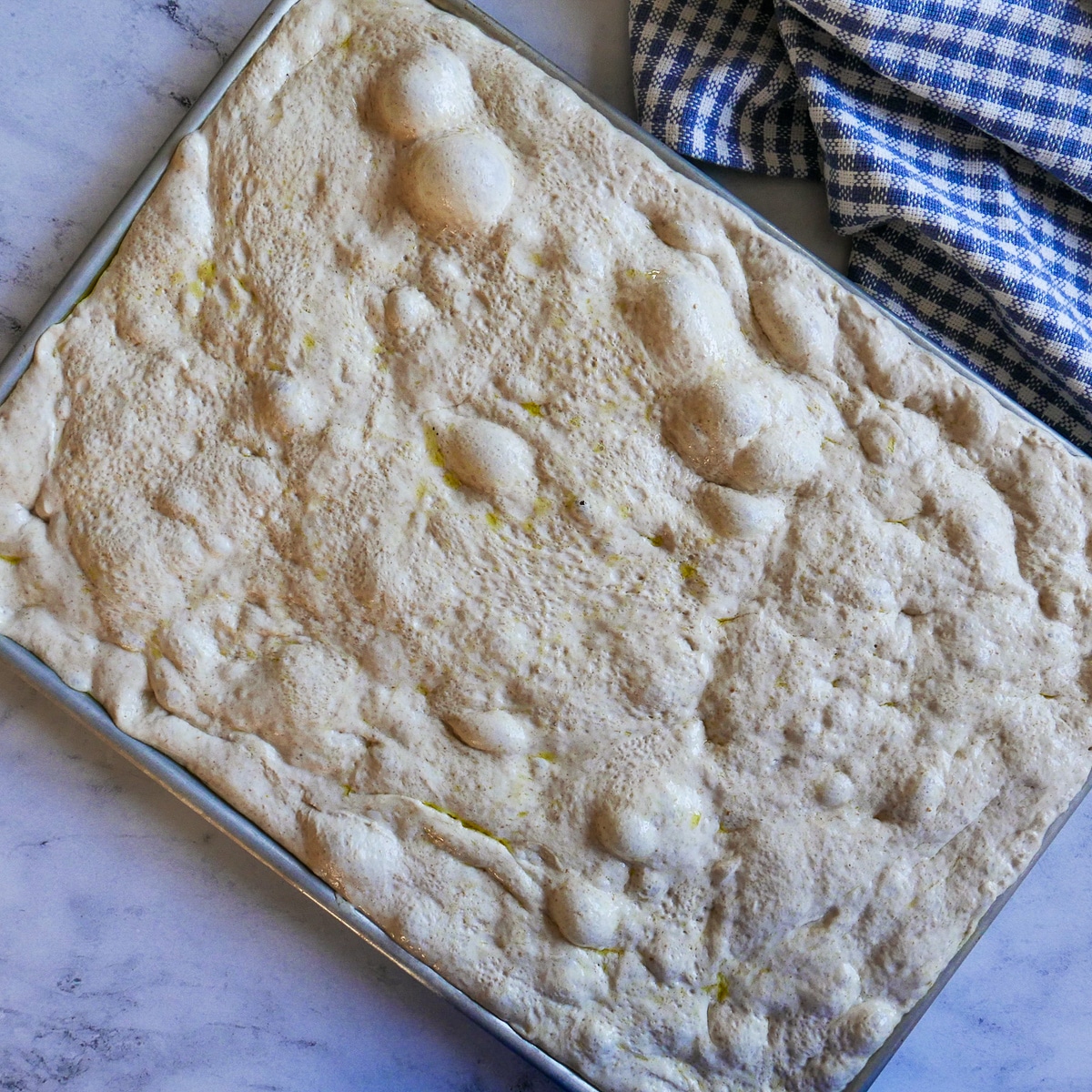 bubbly focaccia dough in a baking sheet