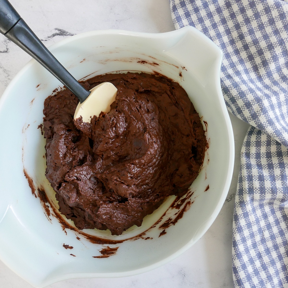 chocolate chips being mixed into cookie dough with a rubber spatula.