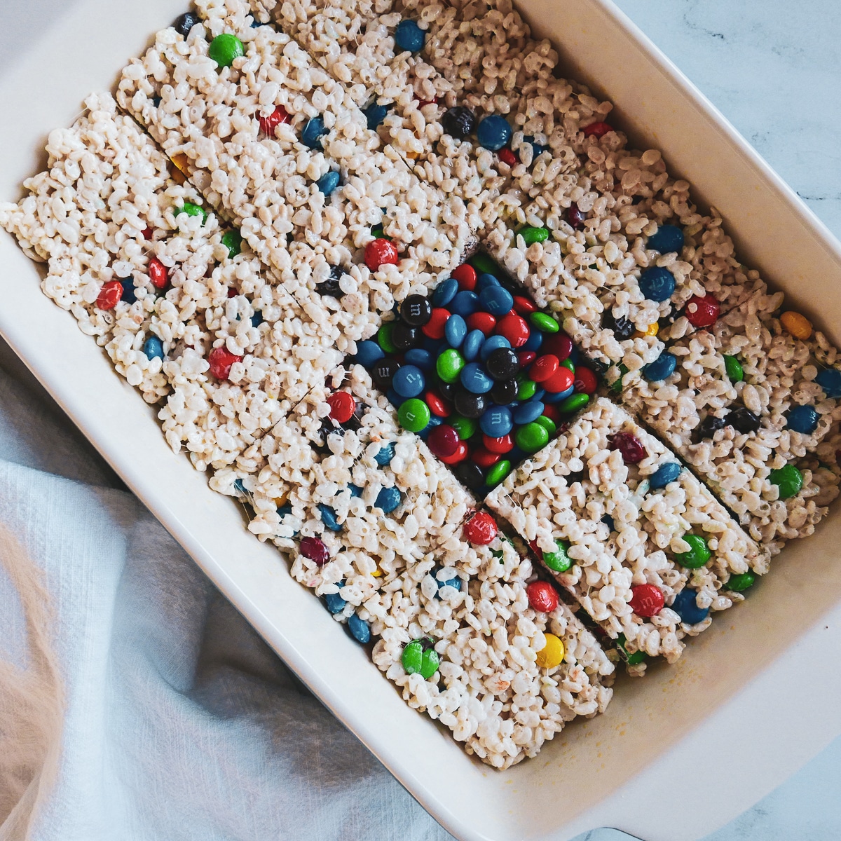 pan of rice krispie treats with m&m's poured into one cut square area.