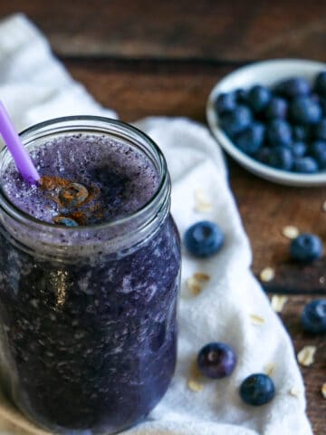 oat milk smoothie in a glass jar with a straw