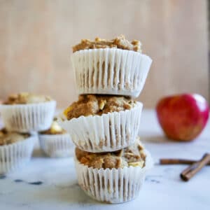 stack of apple muffins with an apple in the background.