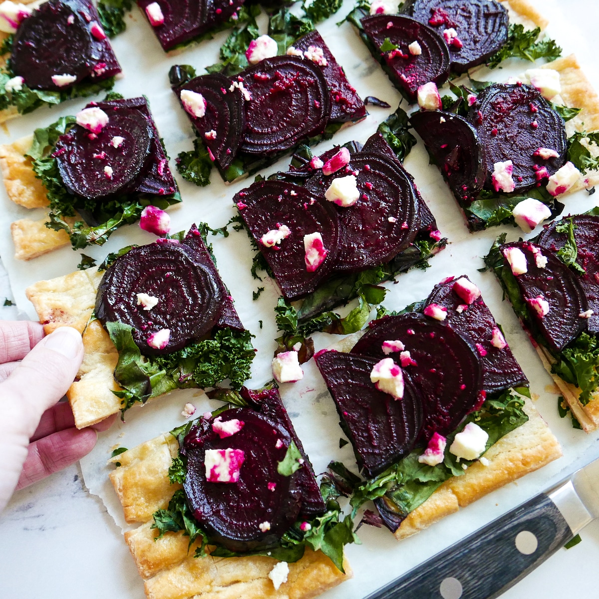 white hand lifting up slice of beet tart.