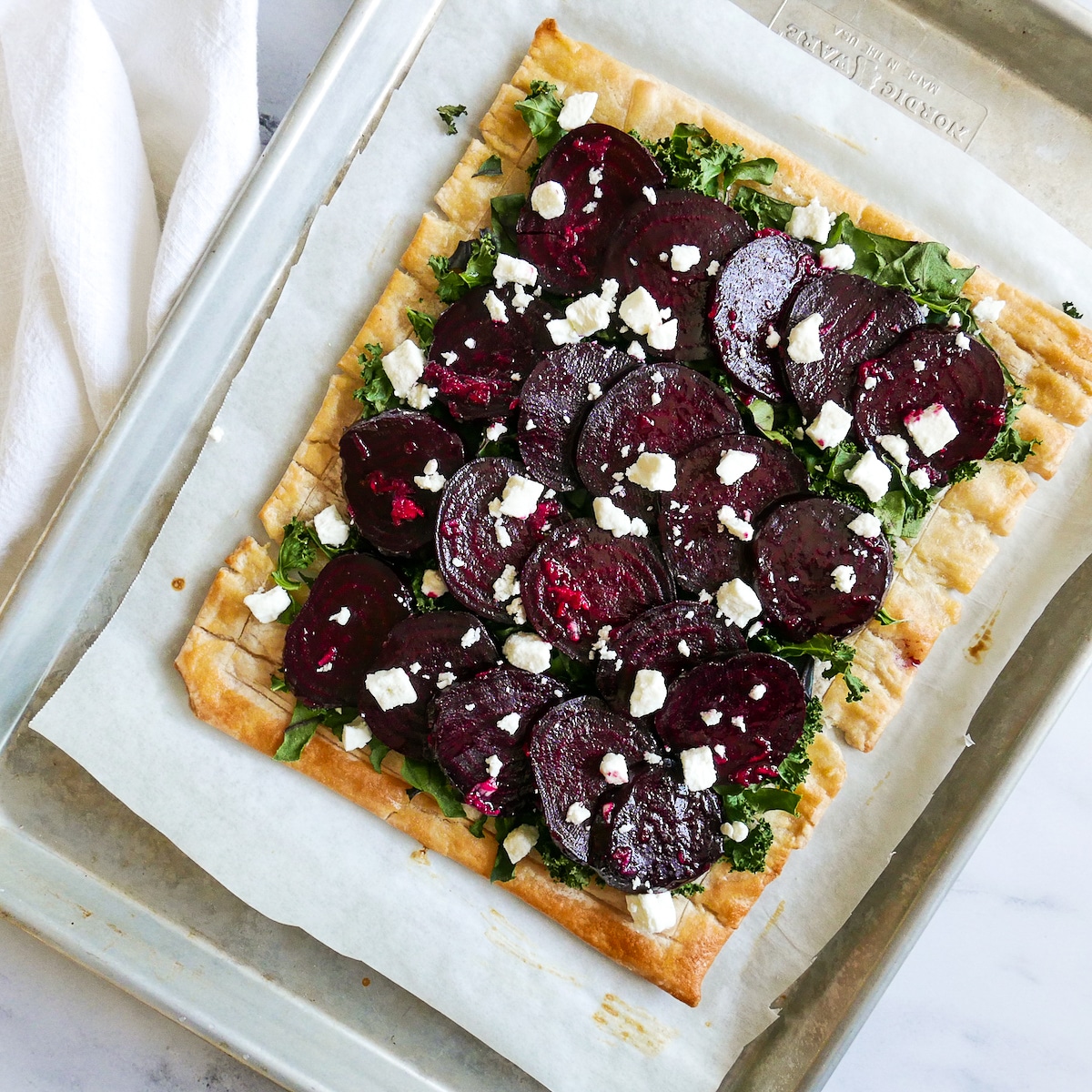 beets, feta, and kale on puff pastry on a baking sheet.
