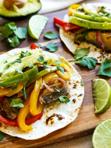 Veggie fajitas arranged on a wooden cutting board.