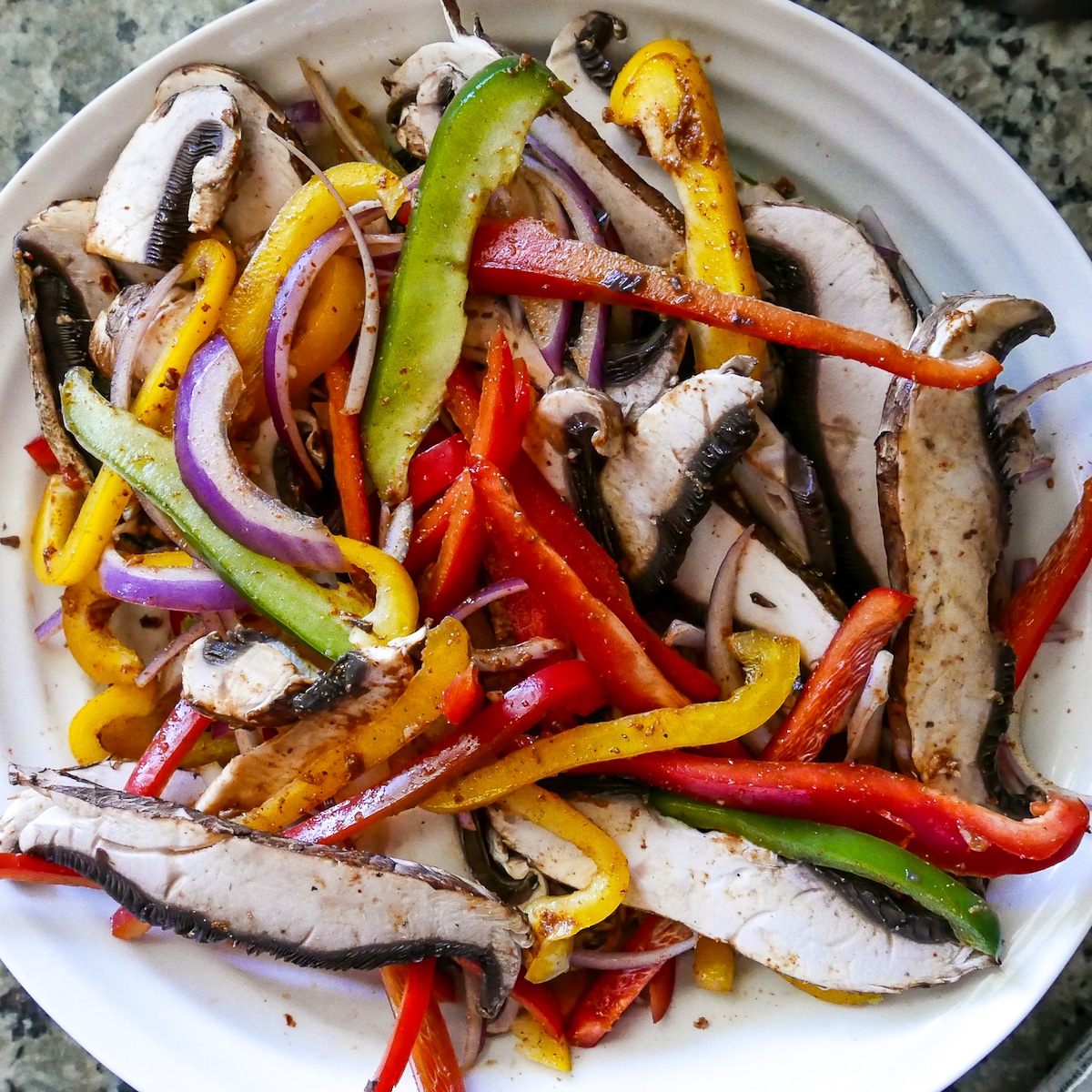 veggies-tossed-in-marinade.jpg sliced peppers, mushrooms, and onion tossed in marinade in large mixing bowl.