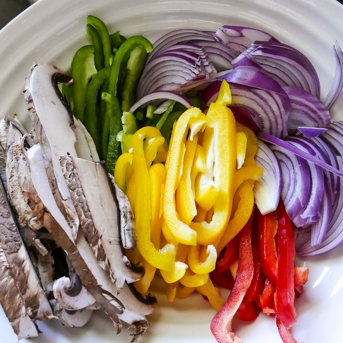 thinly sliced bell peppers, mushrooms, and red onion in a large mixing bowl.