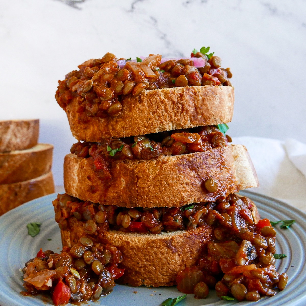 stack of 3 texas toast sloppy joes on a gray plate.