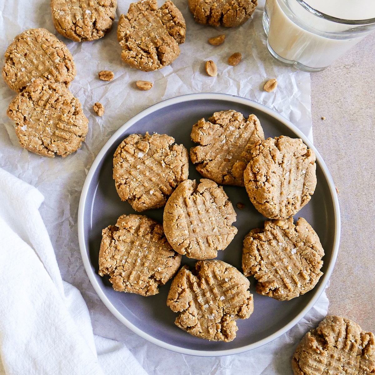 almond flour peanut butter cookies arranged on a gray plate with glass of milk in background.