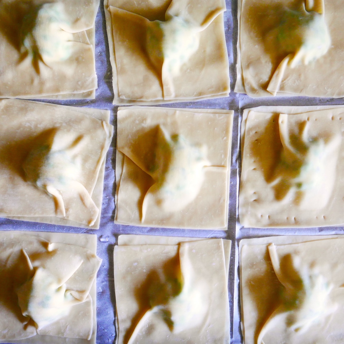 assembled wonton ravioli on a baking sheet.