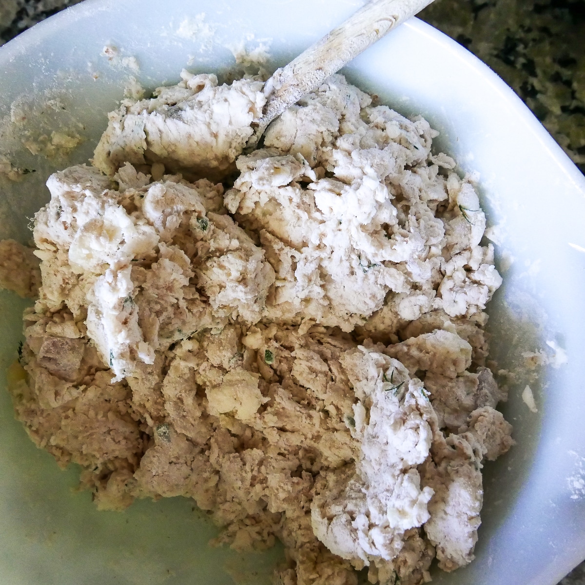 biscuit dough being mixed with a wooden spoon.