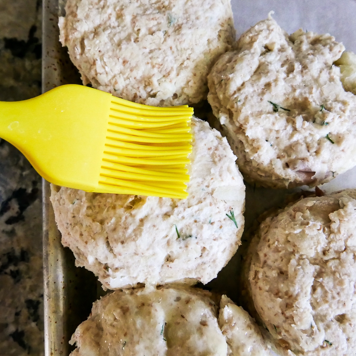 pastry brush adding butter to dill biscuits.