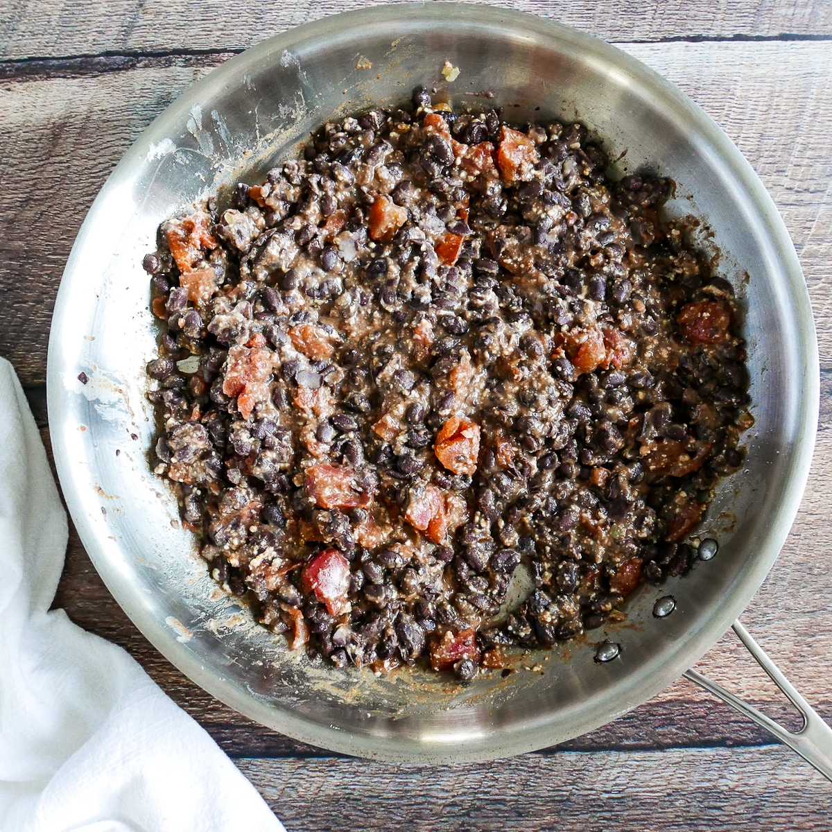 Bean, cheese, and tomato mixture being cooked in a large skillet.