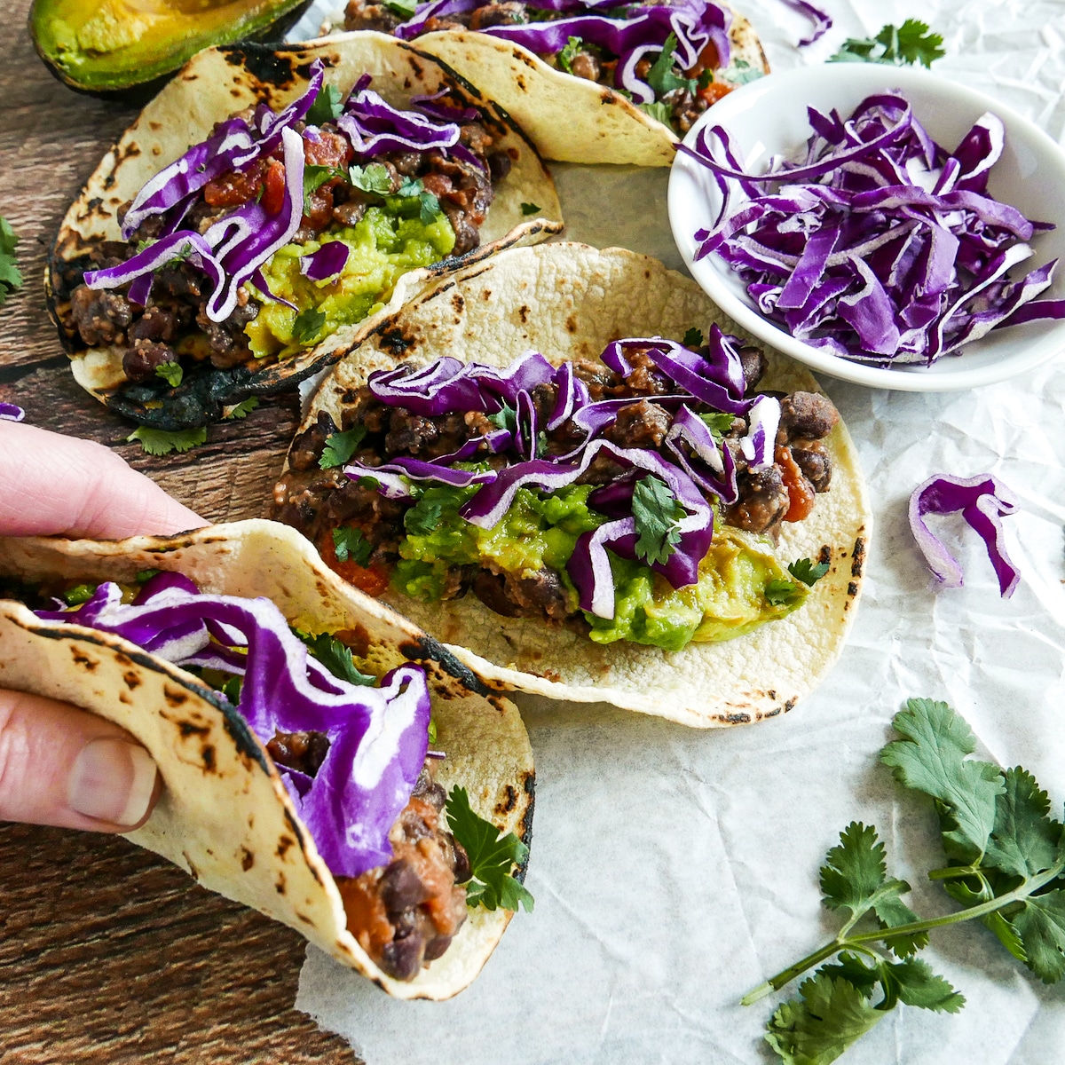 Holding Mexican bean tacos over a table.