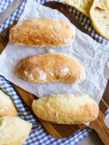 Three homemade ciabatta rolls resting on a cutting board.