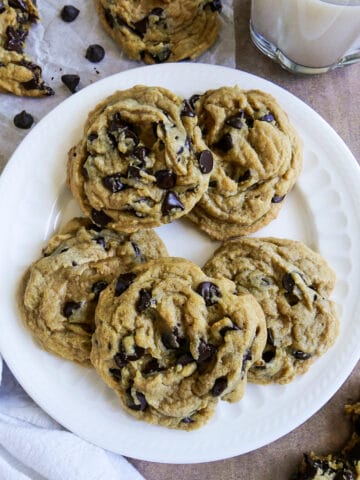 five dairy free chocolate chip cookies arranged on a white plate.