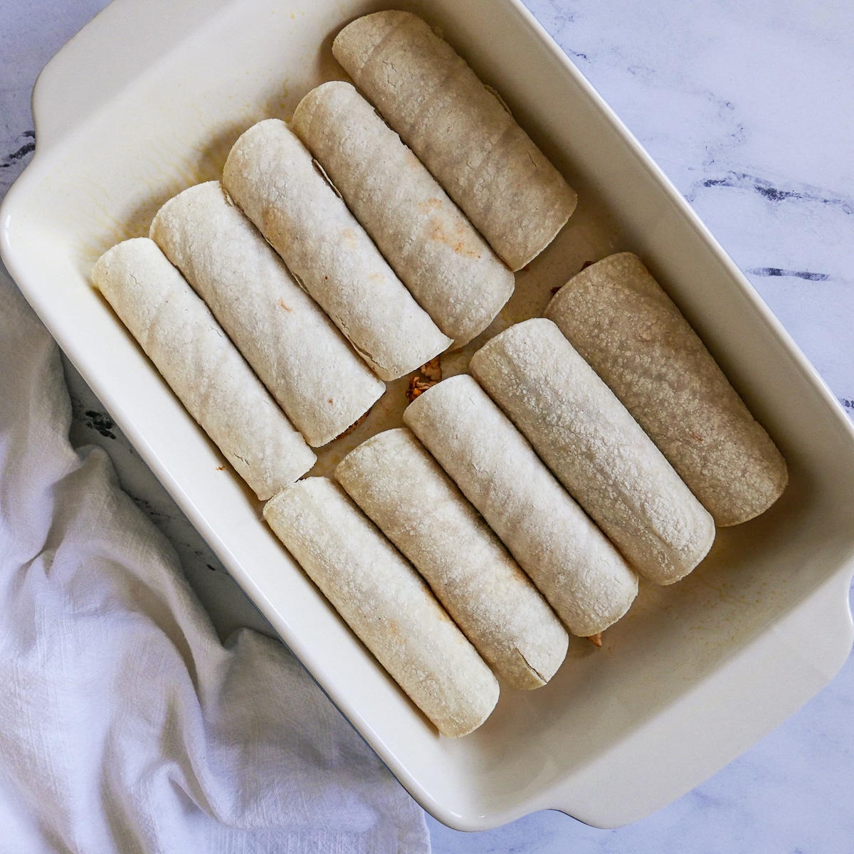 10 enchiladas rolled up and placed in a baking dish.