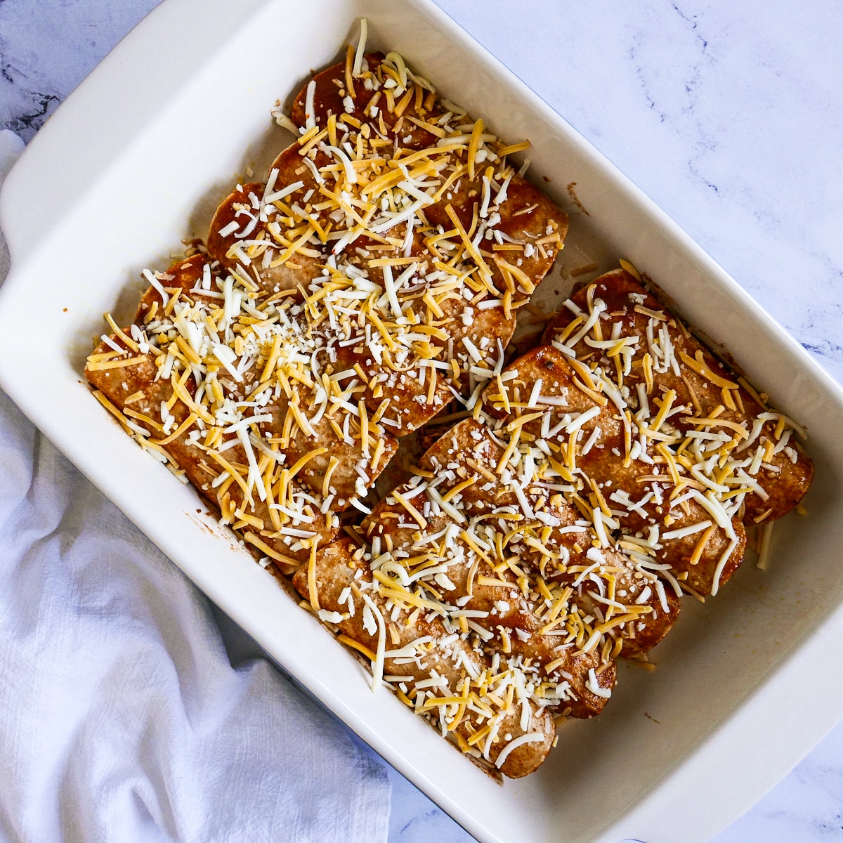 cheese sprinkled on top of assembled enchiladas.