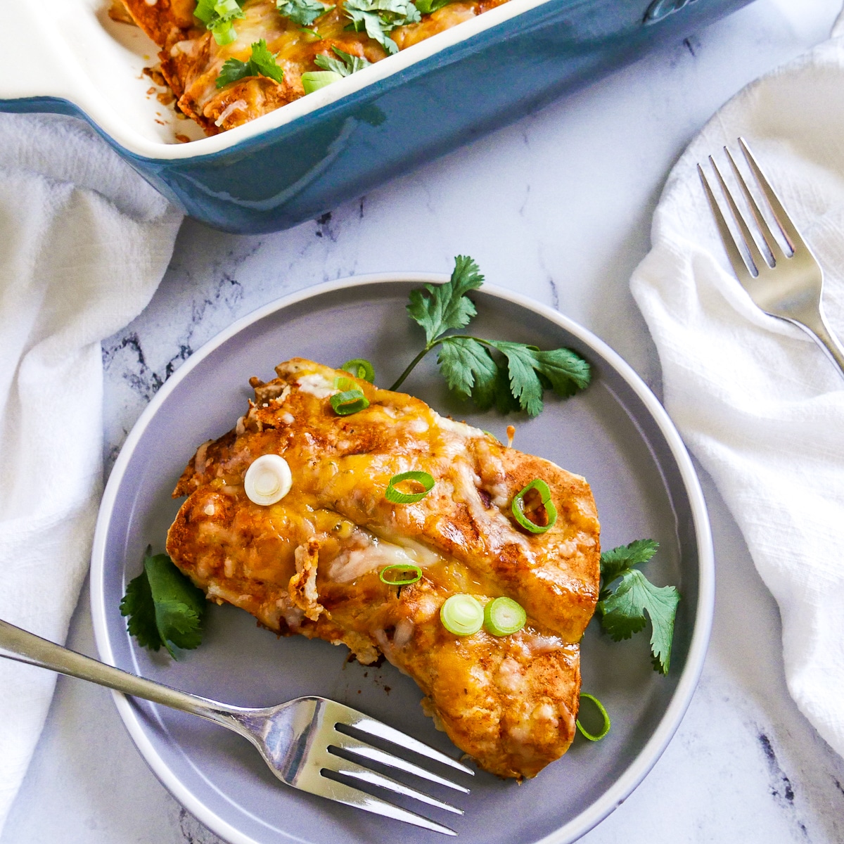 two chicken chipotle enchiladas on a gray plate with fresh cilantro.