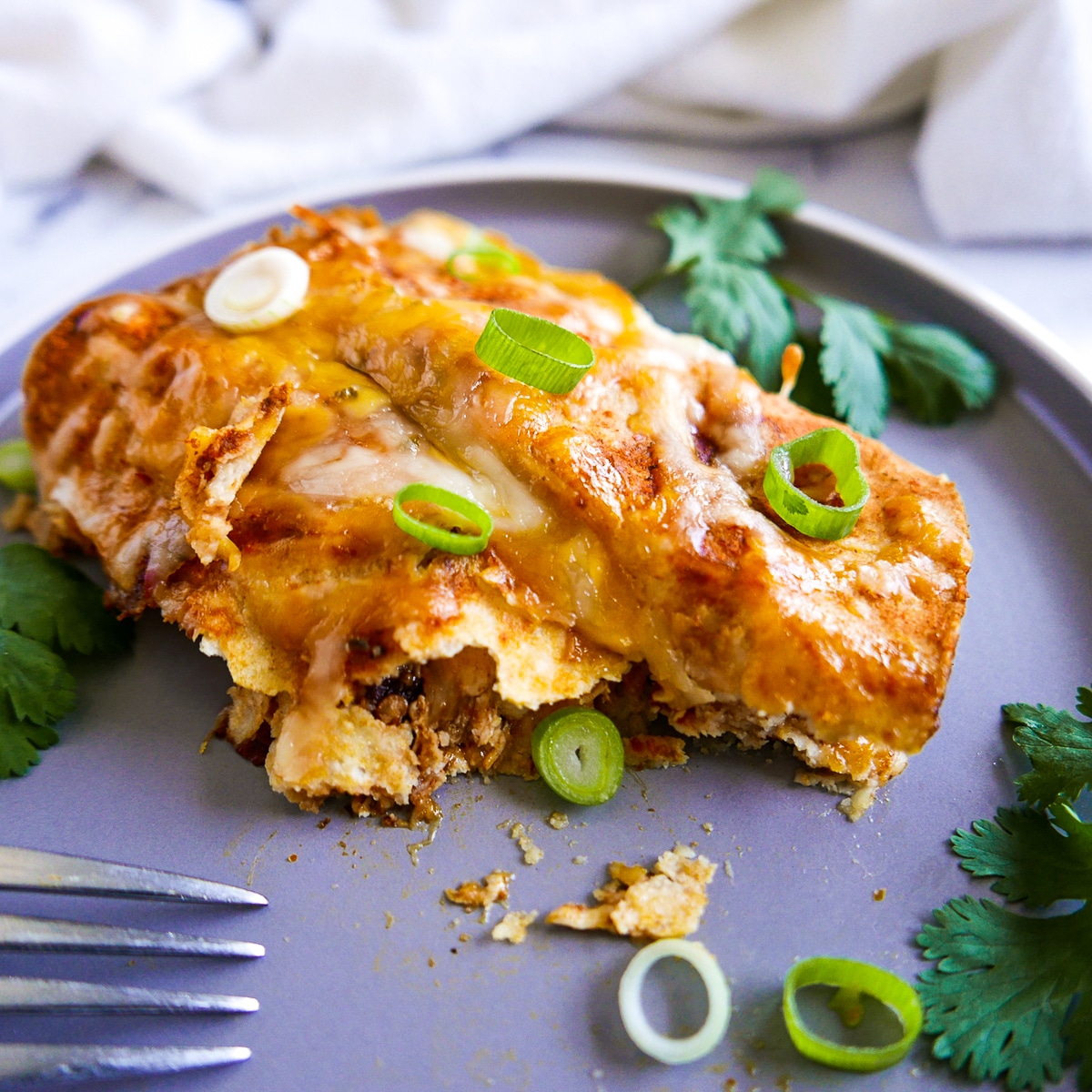 two enchiladas on a plate with one cut into with fork. 