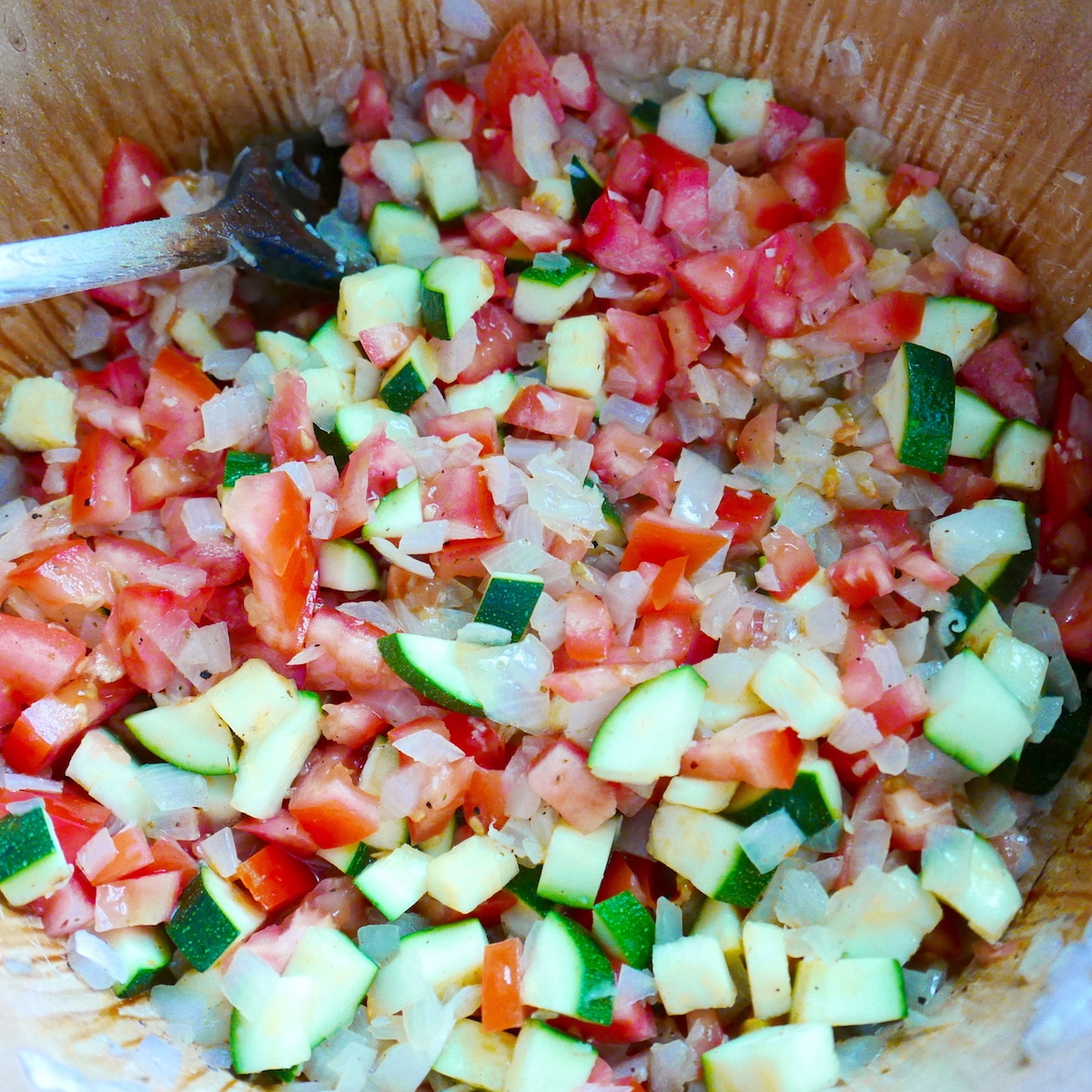 onions, tomato, and zucchini cooking in a Dutch oven. 