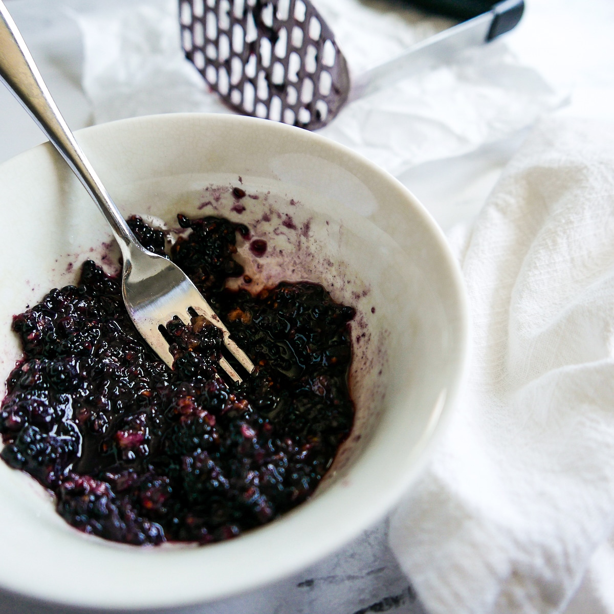 bowl of mashed blackberries with a fork. 