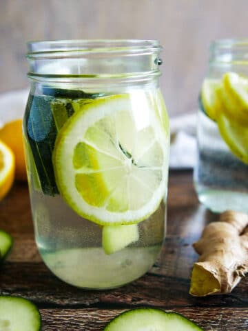 two mason jars with cucumber lemon ginger water.