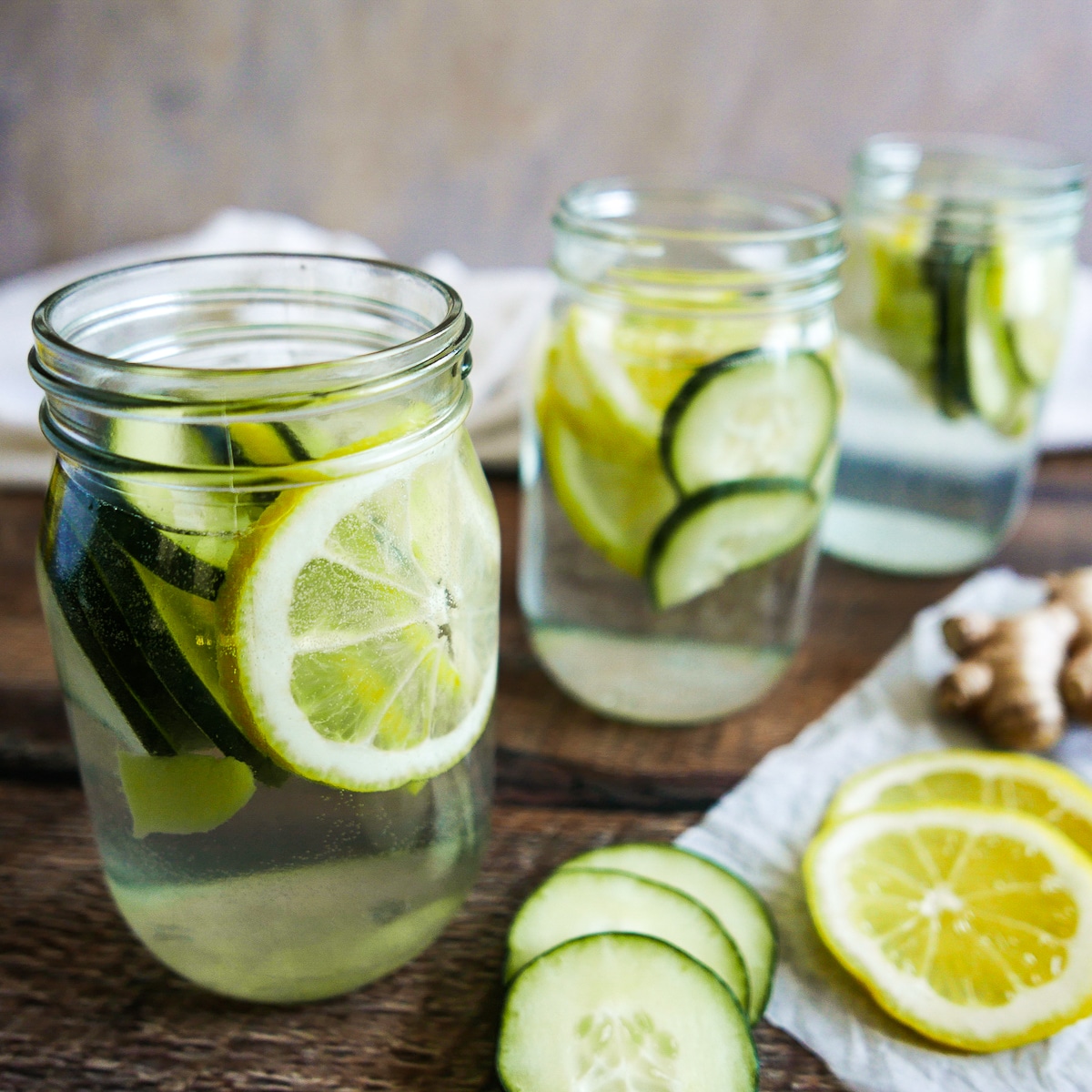 three jars of infused water on a wooden table.