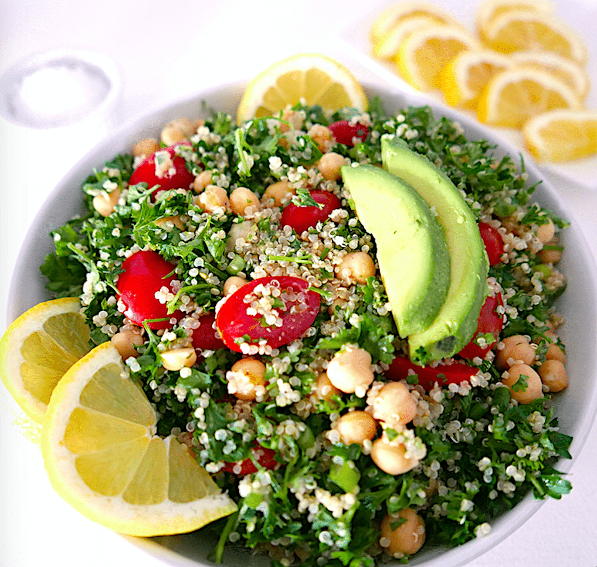 tabbouleh salad with lemon, parsley, and mint, and sliced lemons in the background. 