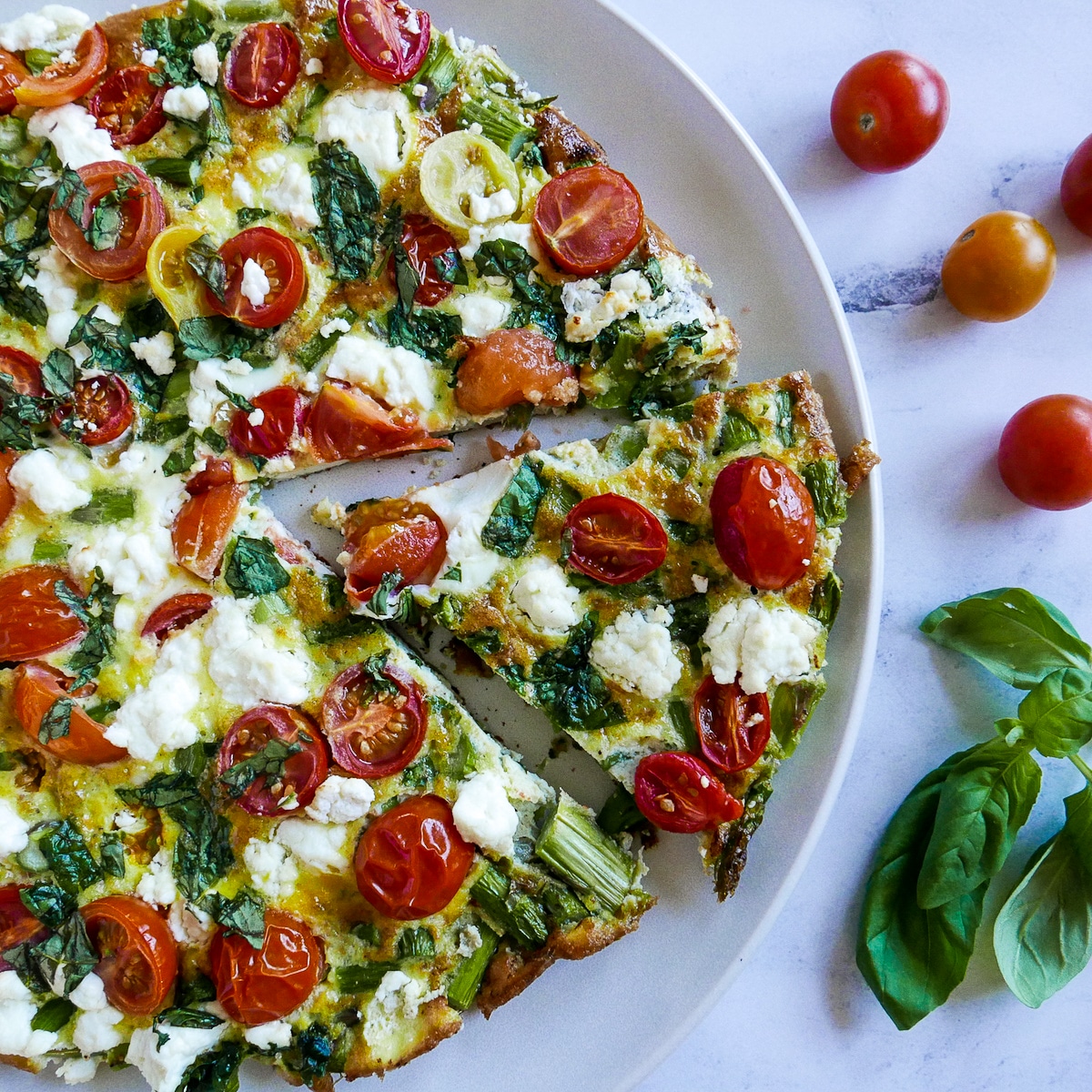 slice-cut-out-of-frittata.jpg one slice cut out of a frittata on a white plate.