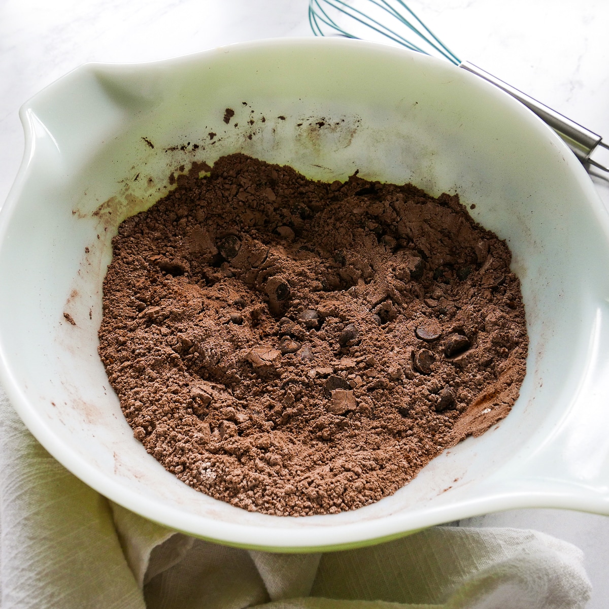 Flour, cocoa powder, baking soda, cinnamon, salt, and chocolate chips mixed in a bowl.