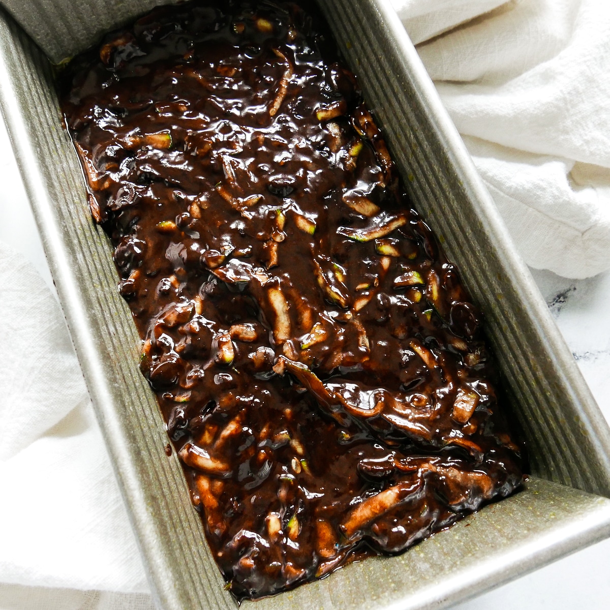 Chocolate zucchini batter spread into prepared loaf pan.