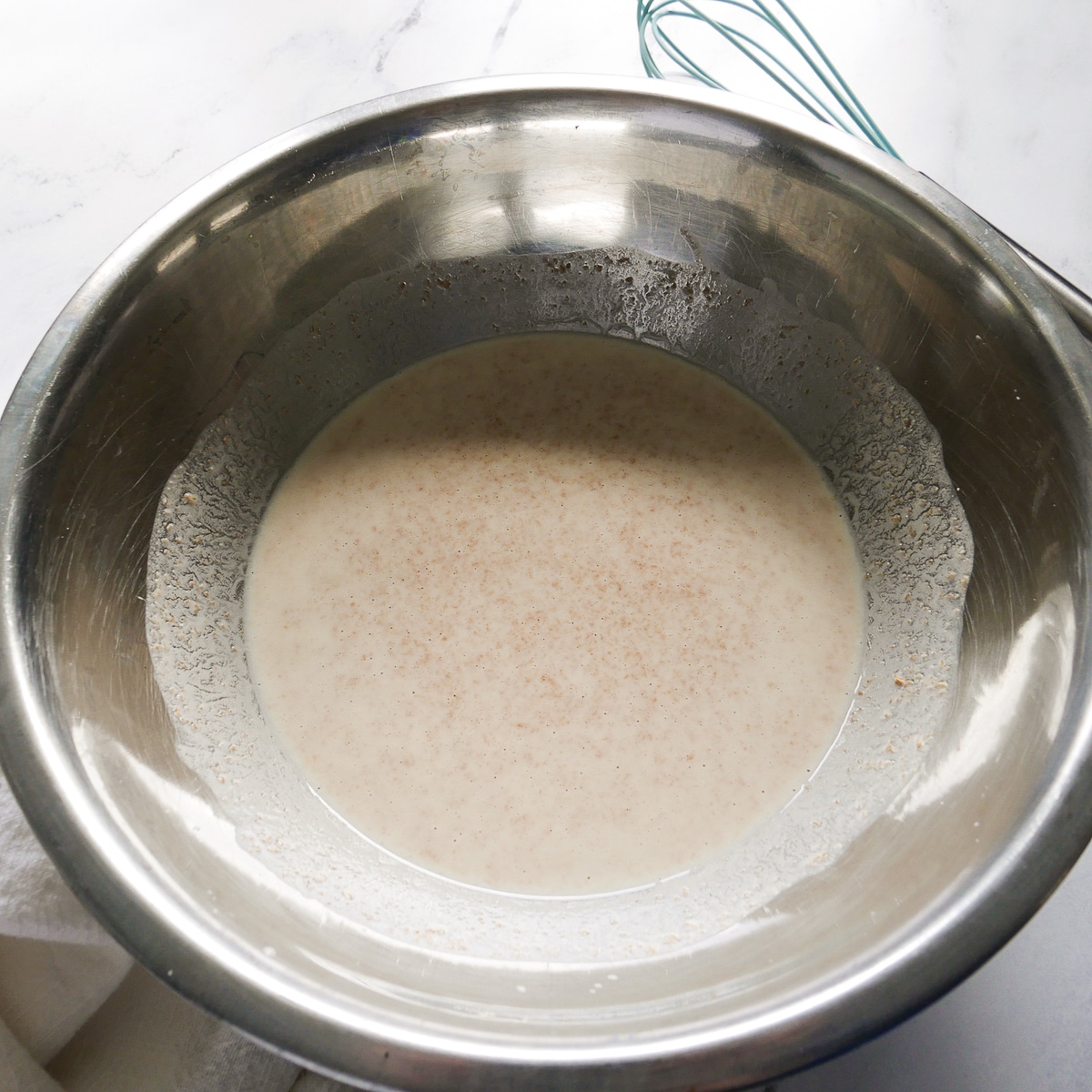 sourdough discard, milk, and yogurt whisked together in a bowl.