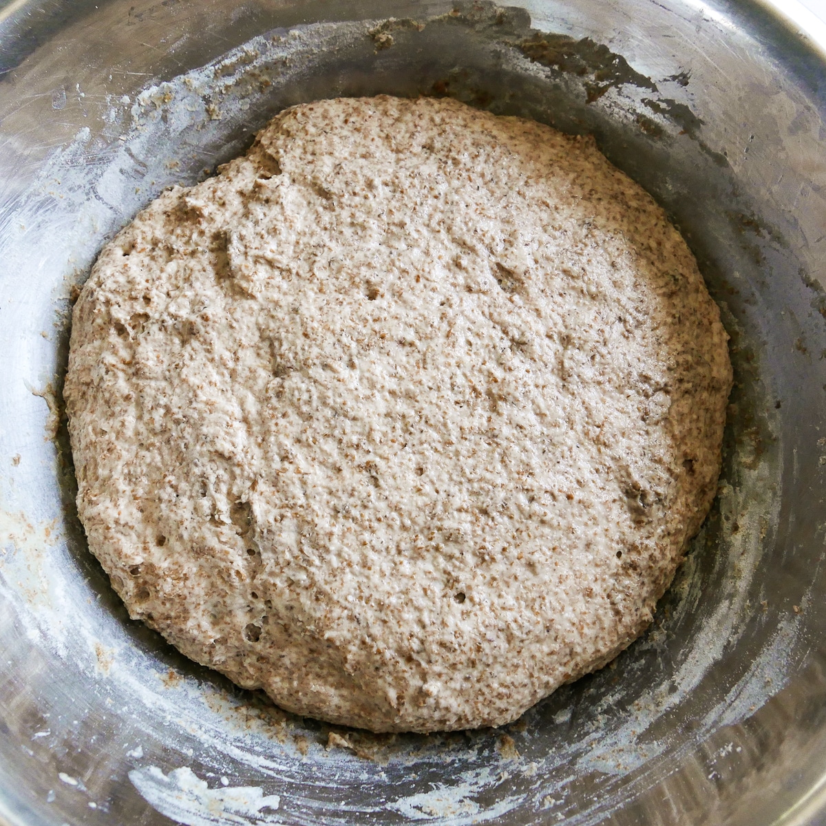 Risen naan dough in a mixing bowl.