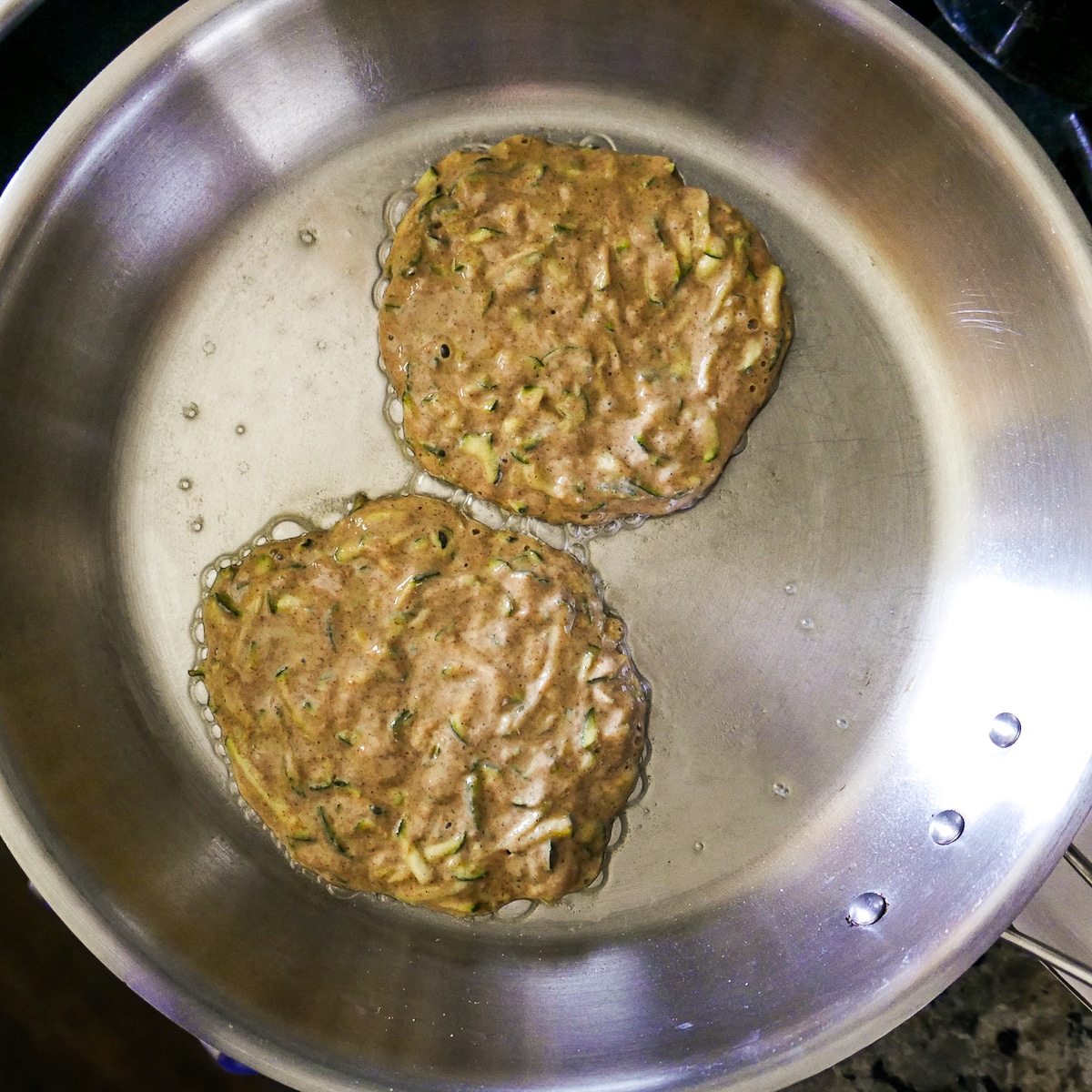 two-pancakes-in-skillet.jpg two pancakes being cooked until bubbly in a large skillet.