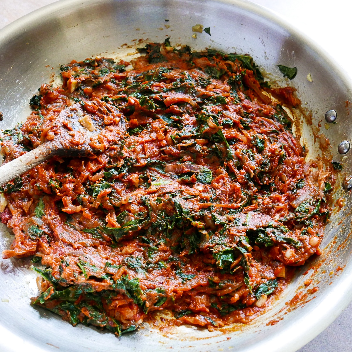 Cooking tomato paste and black pepper into shallot and Swiss chard mixture in a skillet.