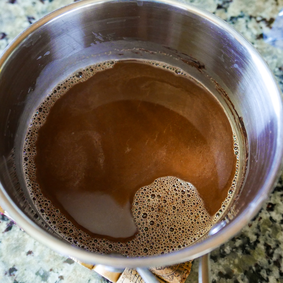 chopped-chocolate-mixed-into-hot-chocolate.jpg Saucepan removed from heat and chopped chocolate whisked into mixture.