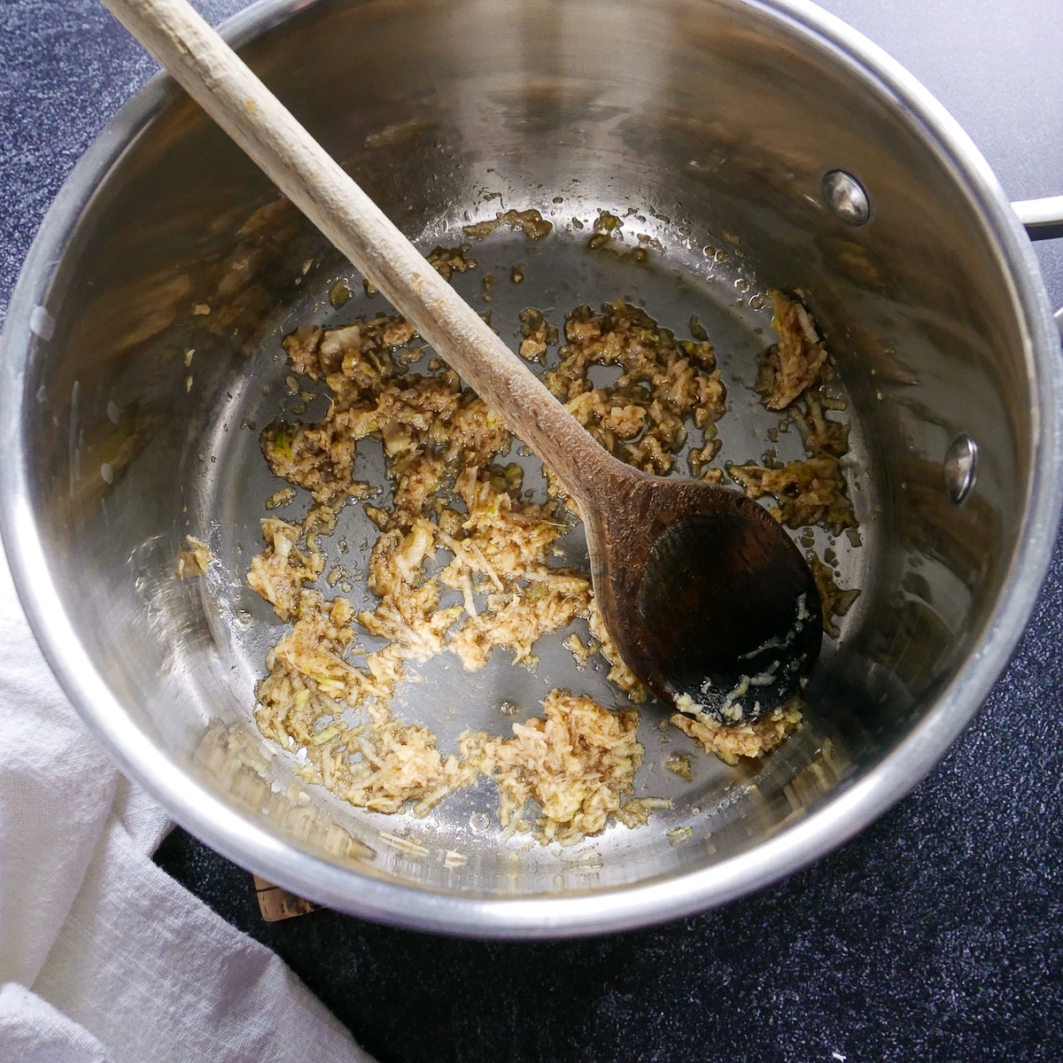 ginger-and-garlic-in-saucepan.jpg Ginger and garlic cooked with sesame oil in a saucepan with a wooden spoon.