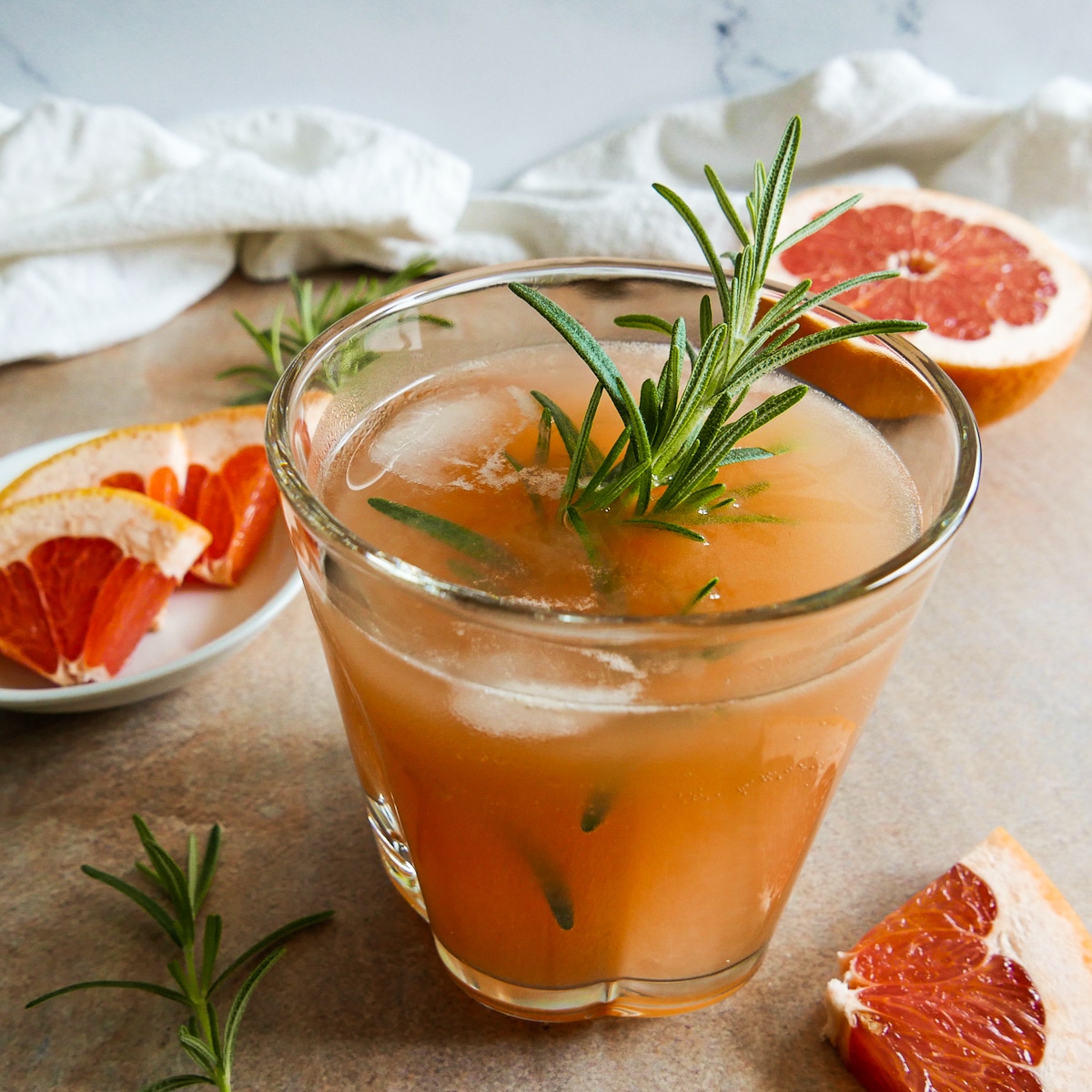 grapefruit cocktail with slices of grapefruit and fresh rosemary on the table.