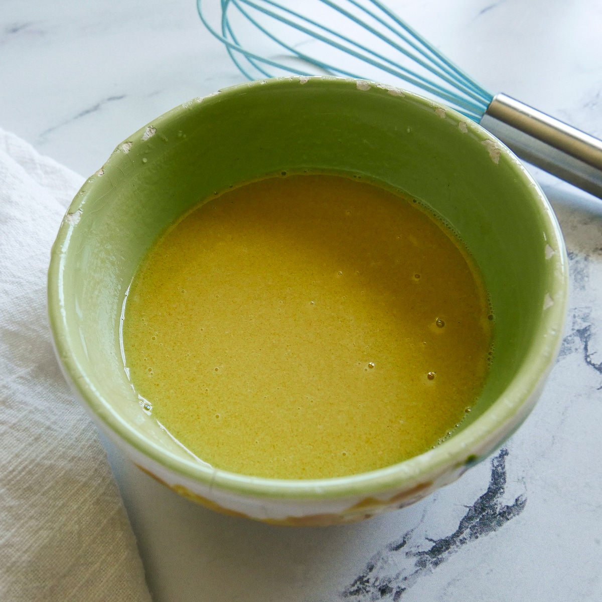 lemon-tahini-dressing.jpg Lemon tahini dressing in a small bowl with a blue whisk in the background.