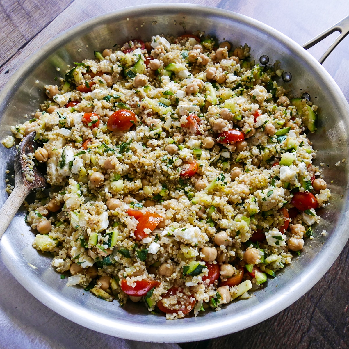 Chickpeas, tomatoes, quinoa, and feta added to onion mixture in a large skillet.