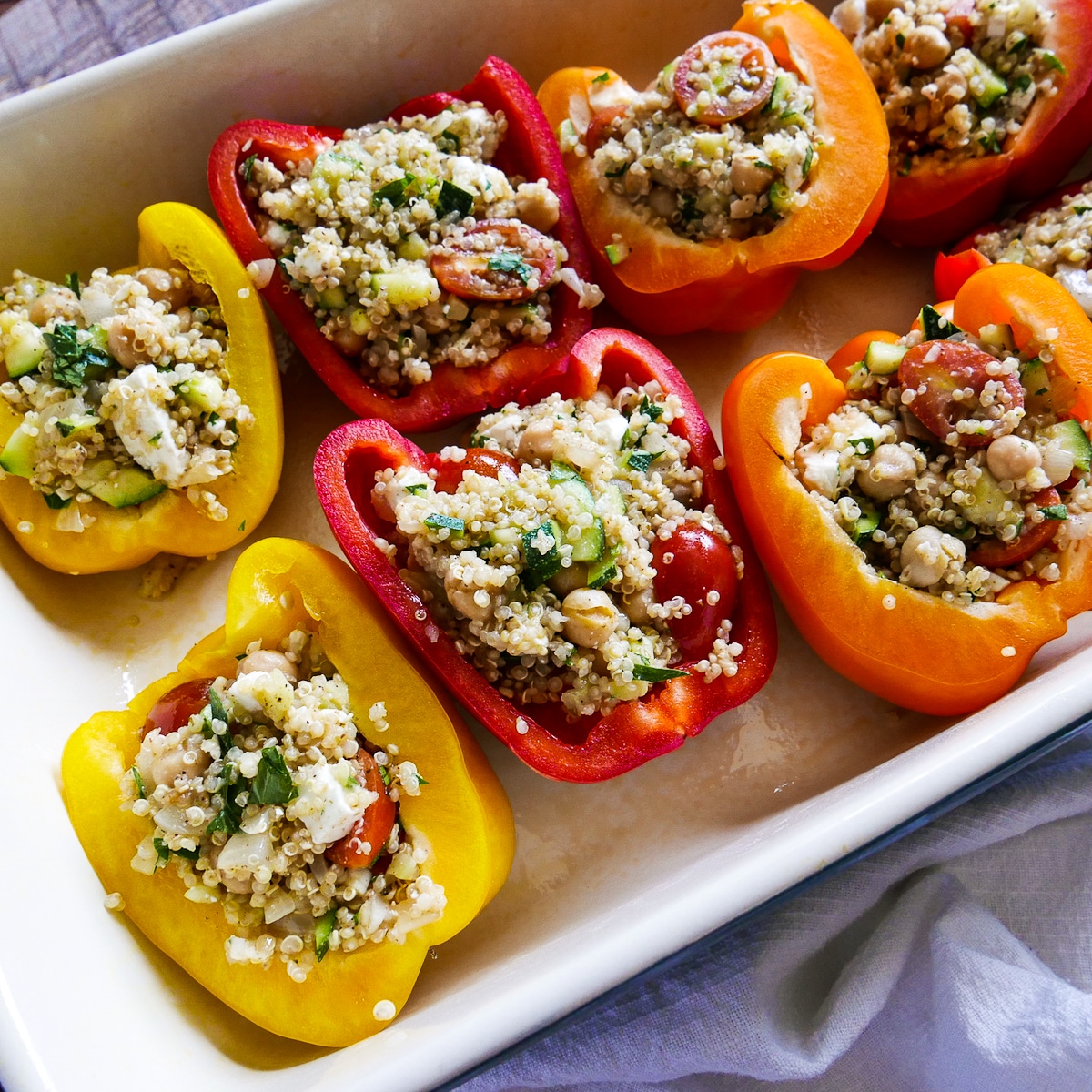 Bell peppers filled with quinoa mixture in a baking dish.