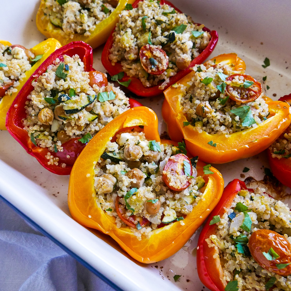 Baked stuffed peppers garnished with fresh parsley in a baking dish. 