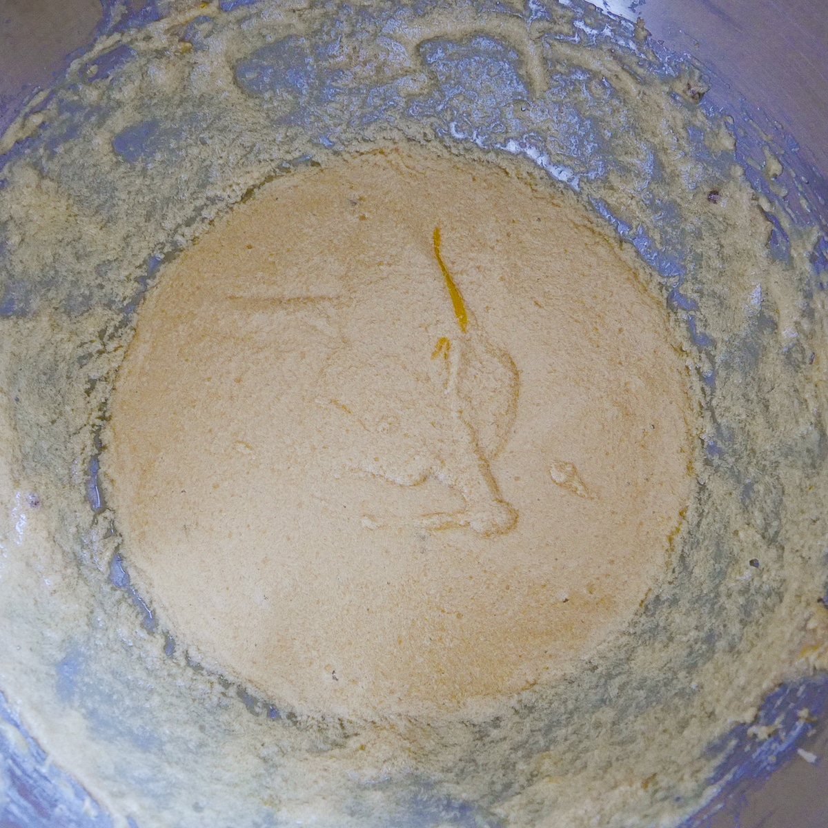 Eggs and vanilla mixed into cake batter in the bowl of a stand mixer. 