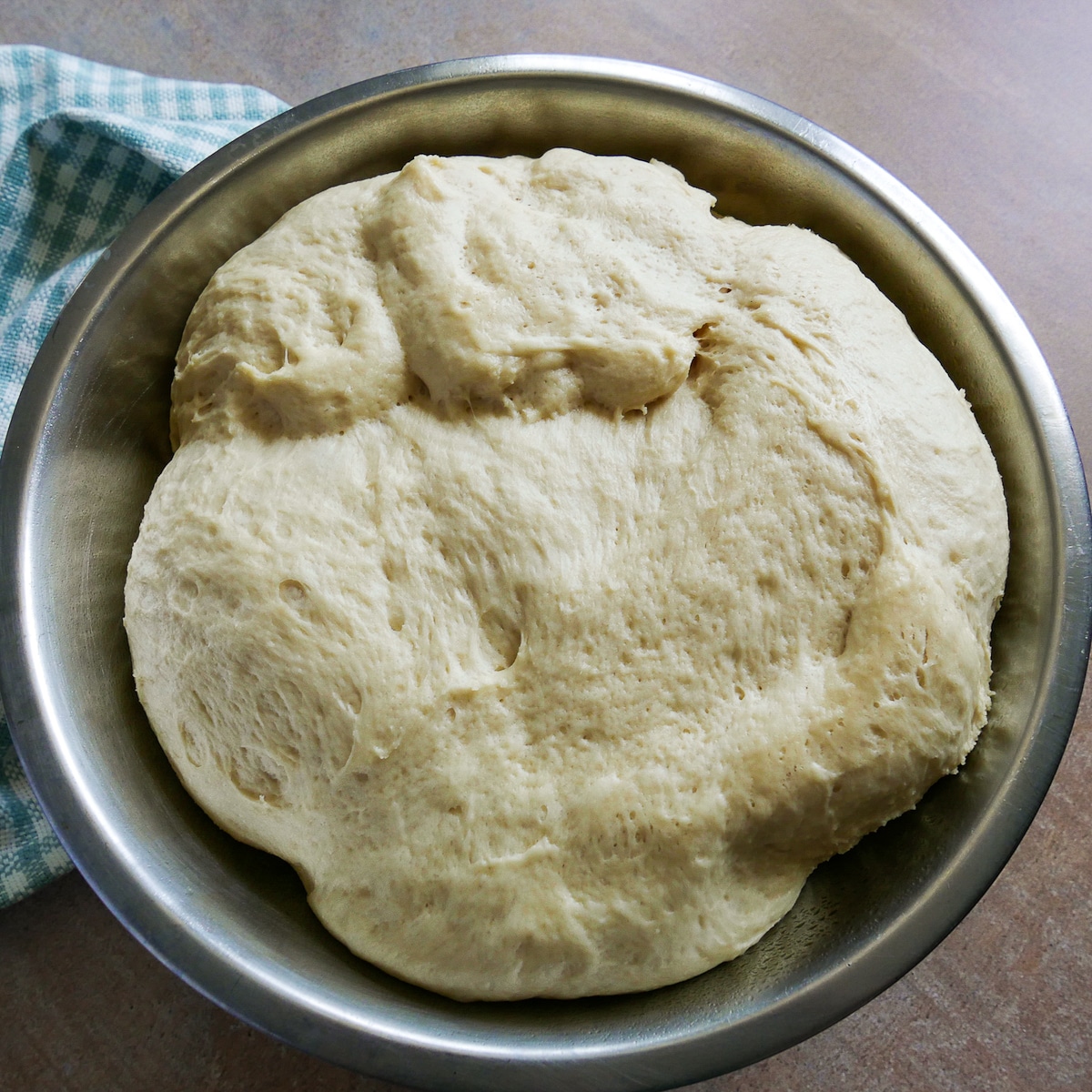 Cinnamon roll dough resting in a bowl after doubling in size. 